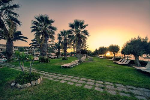 a park with benches and palm trees at sunset at D'Andrea Mare Hotel in Ialyssos