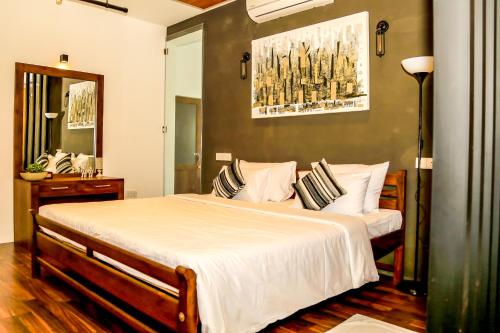 um quarto com uma cama grande com lençóis brancos e almofadas em Eden Studio Apartments - 1 em Colombo