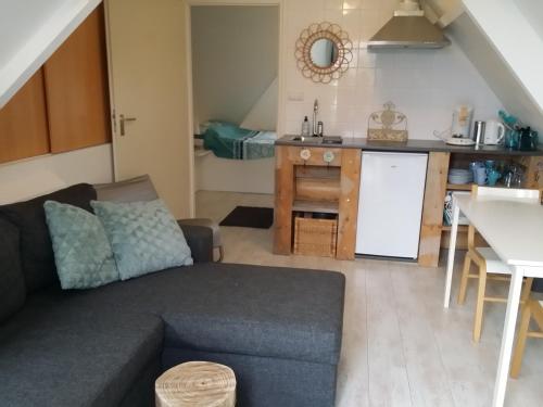 a living room with a couch and a kitchen at Gastenverblijf appartement tussen Alkmaar en Hoorn in Oterleek