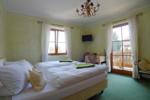 a bedroom with a bed with white sheets and windows at Gästehaus Baier am Bad in Bad Wiessee