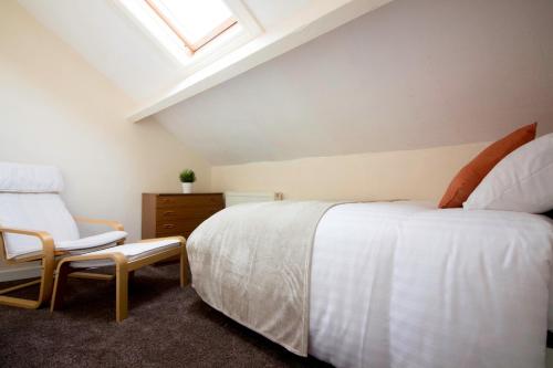 a bedroom with a white bed and a chair at Brook House in Selby