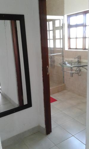 a bathroom with a shower and a mirror on a wall at Elegant Guest House Malelane in Malelane