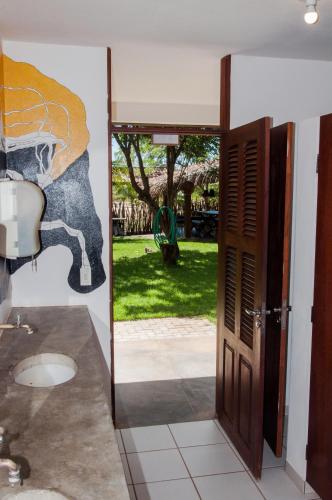 a door leading to a yard with a painting on the wall at Jangada Lodge in São Miguel do Gostoso