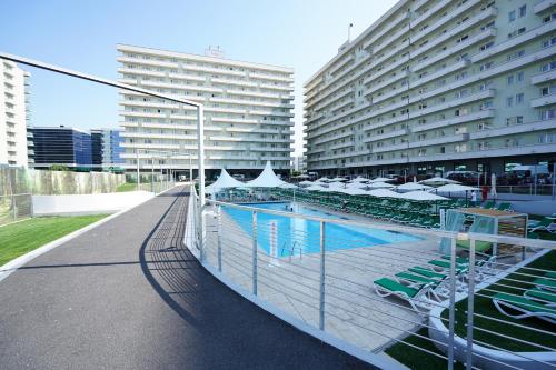 a pool with chairs and umbrellas next to two tall buildings at West Gate Studios in Bucharest