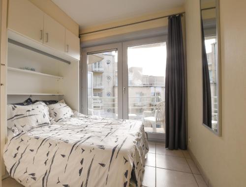 ein Schlafzimmer mit einem Bett und einem großen Fenster in der Unterkunft Appartement Zeezicht in Ostende