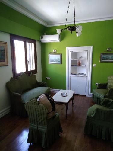 a living room with green walls and a table and chairs at Acropolis Apartment in Athens