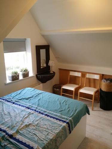 um quarto com uma cama, 2 cadeiras e uma janela em VAKANTIEHUISJE Daar bij de Molen tussen Alkmaar en Hoorn em Oterleek