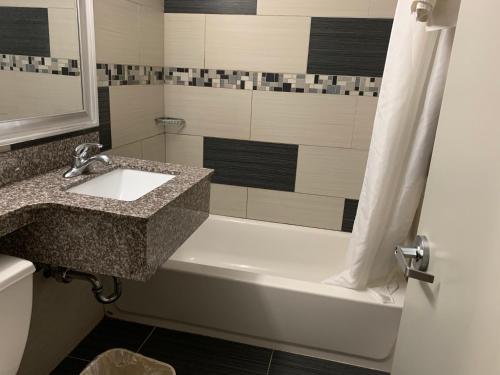 a bathroom with a sink and a bath tub at Red Carpet Inn Elmwood in Elmwood Park