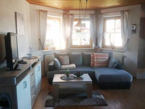 ein Wohnzimmer mit einem blauen Sofa und einem Tisch in der Unterkunft Ferienwohnung Stöberl Gerda in Lohberg