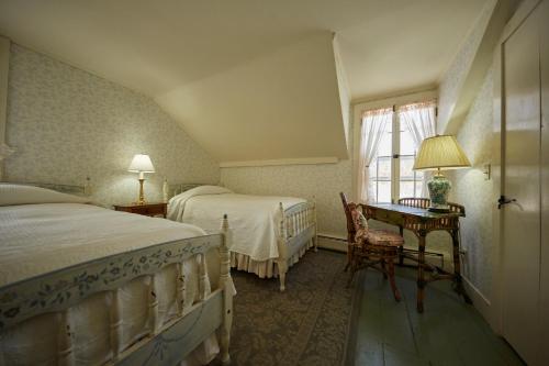 a bedroom with two beds and a desk and a window at The Red Lion Inn in Stockbridge