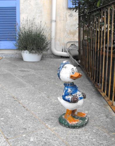 a plastic duck statue on a sidewalk next to a gate at B&B Del Piazzo in Biella