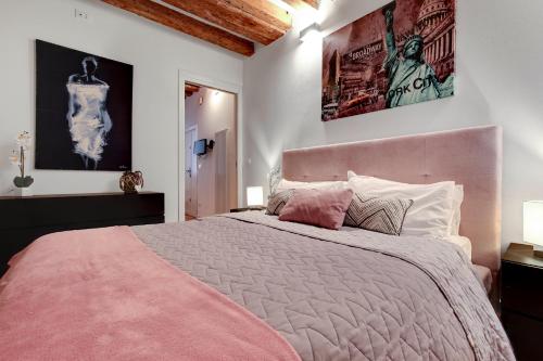 1 dormitorio con 1 cama rosa y 2 posters en la pared en Charming Castello Apartments, en Venecia