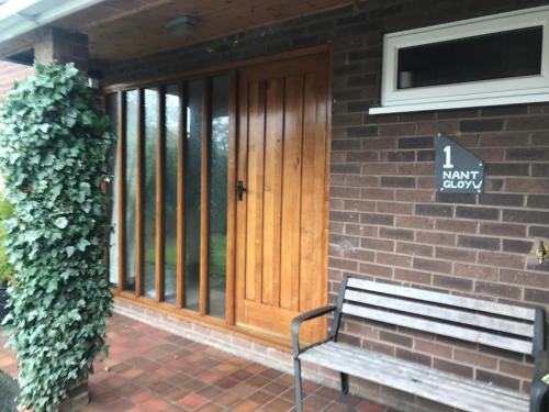 a wooden door on a brick building with a bench at Nant Gloyw Oswestry in Oswestry