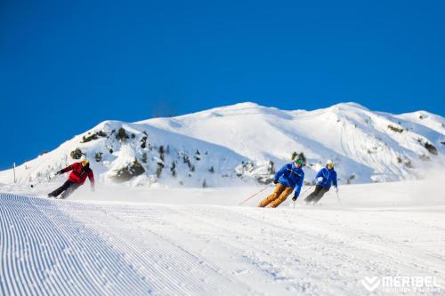 a group of three people skiing down a snow covered slope at Hotel La Chaudanne in Méribel