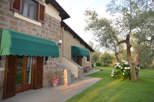 a building with a green awning next to a yard at Agriturismo I Due Casali in Vetralla