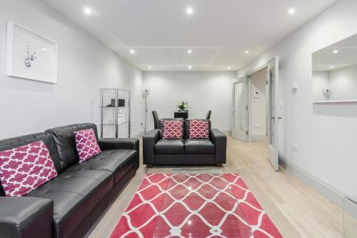 a living room with a black couch and a red rug at Roomspace Serviced Apartments - The Quadrant in Richmond upon Thames