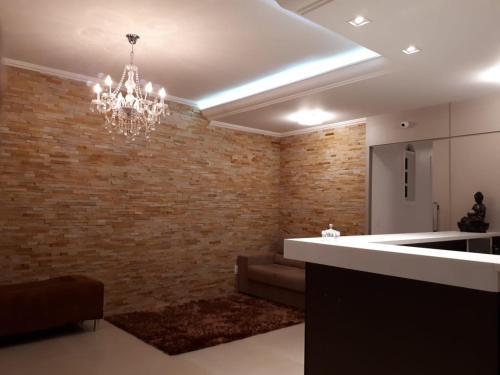 a living room with a brick wall and a chandelier at Pousada Hospedagem Palhoça in Palhoça