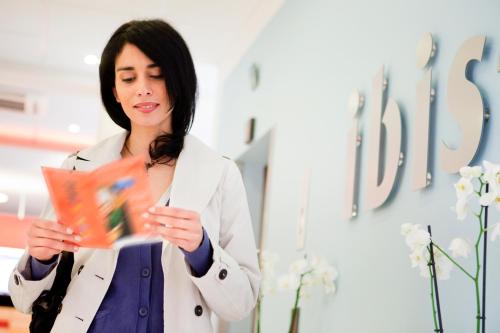 a woman in a white coat reading a book at Ibis Barcelona Meridiana in Barcelona