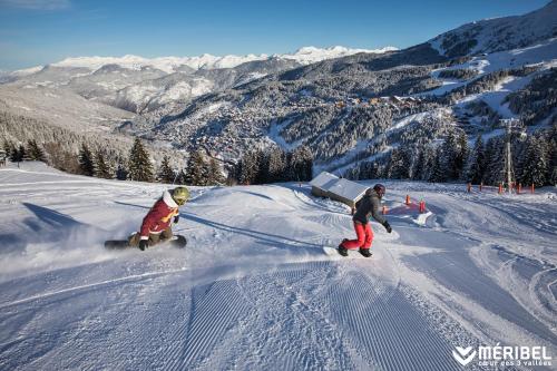 two people are snowboarding down a snow covered slope at Le Kaïla in Méribel