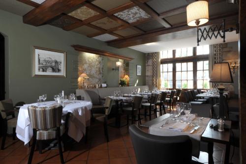une salle à manger avec des tables et des chaises avec des nappes blanches dans l'établissement Hôtel de France, à Ornans