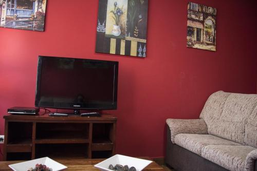 a living room with a flat screen tv and a couch at Apartahotel Rural CollaRubio Luxury in Collado Mediano