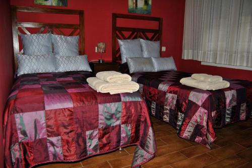 two beds in a red room with towels on them at Apartahotel Rural CollaRubio Luxury in Collado Mediano