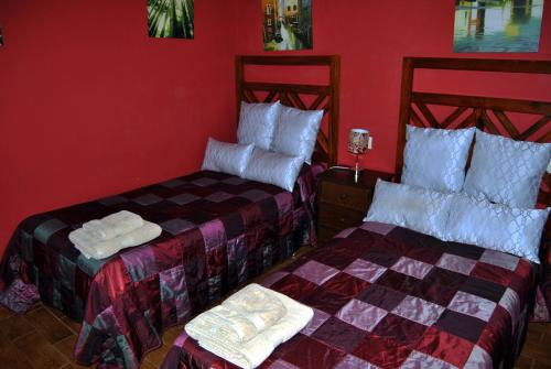 two beds in a room with red walls at Apartahotel Rural CollaRubio Luxury in Collado Mediano