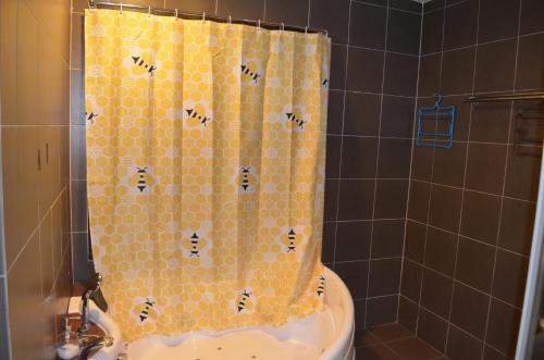 a shower with a yellow tiled shower curtain with bees at Gold Coast Morib Ain Studio in Kampong Tanjong Pechah
