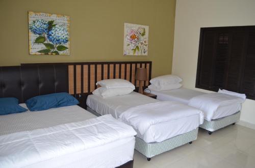 três camas num quarto com lençóis brancos em Gold Coast Morib Ain Studio em Kampong Tanjong Pechah