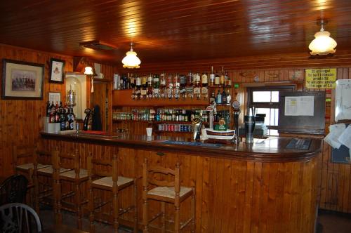 un bar con paredes de madera y una barra de madera con sillas en The Neuk, en Portlethen