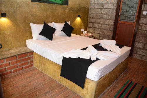a bedroom with a bed with white sheets and black pillows at Negombo The Nature Villa and Cabanas in Negombo