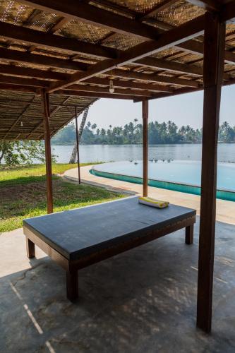a bench under a pavilion with a view of a lake at Cranganor History Café & Riverside Château in Parūr