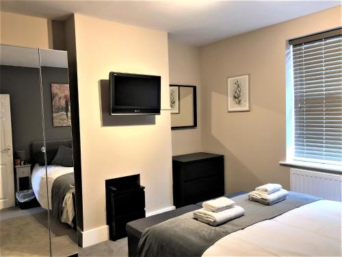 Eclipse Apartment No 2 في نيوماركت: غرفة نوم بسرير وتلفزيون على جدار