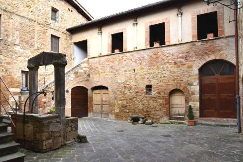 a large brick building with a door and a courtyard at Residenza storica il Pozzo in San Quirico dʼOrcia