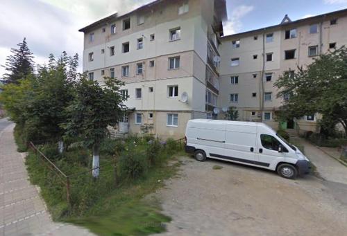 una furgoneta blanca estacionada frente a un edificio en Apartment Valea Azugii, en Azuga