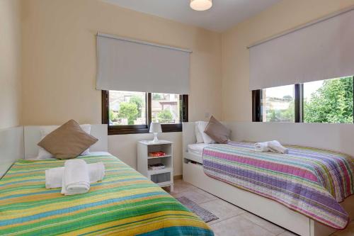 two beds in a room with two windows at Villa Pashiana in Polis Chrysochous