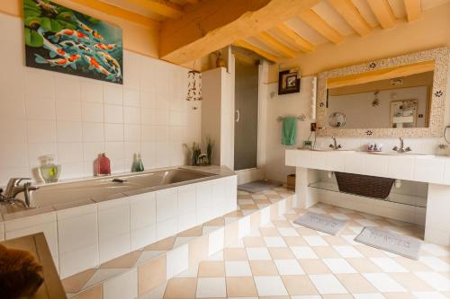 a bathroom with a tub and two sinks and a mirror at la maison d'idylle in Combourg