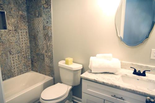 a bathroom with a toilet and a sink and a tub at The Orange Door-Sleeps 10 in Louisville
