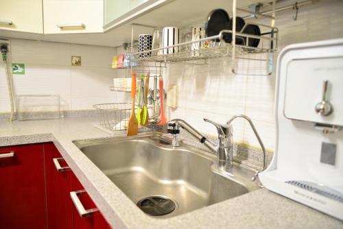 a kitchen with a stainless steel sink and red cabinets at Yeonnam Minbak in Seoul