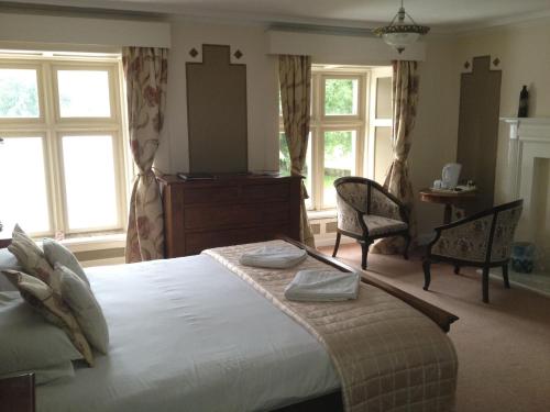 a bedroom with a large bed with two chairs and windows at Clennell Hall Country House - Near Rothbury - Northumberland in Alwinton