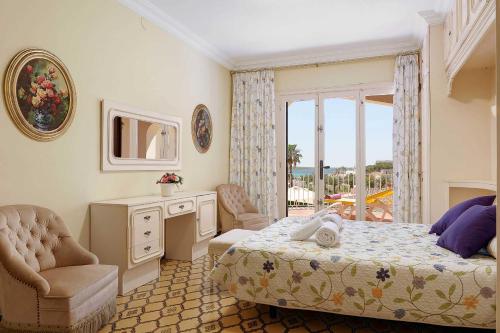 a bedroom with a bed and a chair and a window at Villa Fantasia in Punta Prima