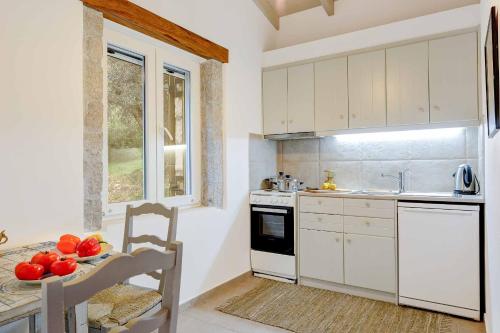 シヴォタにあるVilla Ledakiのキッチン(白いキャビネット、フルーツボウル付きのテーブル付)