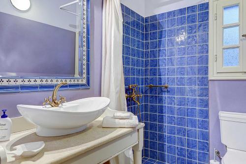 La salle de bains est pourvue d'un lavabo et d'un mur carrelé bleu. dans l'établissement Villa Persephone, à Andipáta Erísou