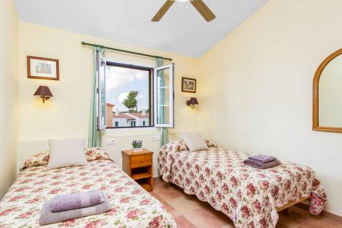 two beds in a room with a window at Villa Marcolis Mar in Cala Galdana