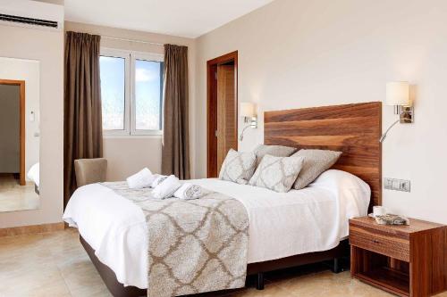 a bedroom with a white bed with a wooden headboard at Blue Dream in Cala en Forcat