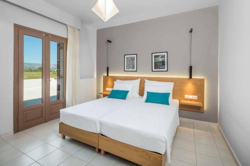 a bedroom with a large white bed with blue pillows at Villa Orchard in Ambelókipoi
