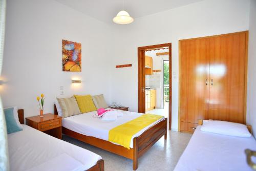 een slaapkamer met 2 bedden en een deur naar een balkon bij Cape Blue Apartments in Paralía Skotínis