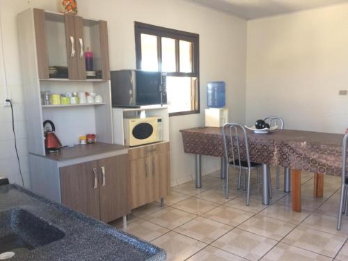 a kitchen with a table and a counter with a microwave at Casa à Beira Mar para Temporada in Sombrio