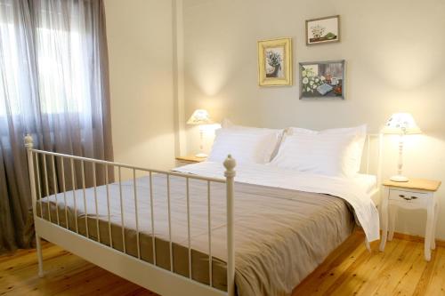 1 dormitorio con 1 cama con ropa de cama blanca y 2 lámparas en Flamouria, en Agios Nikolaos