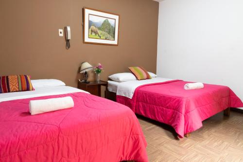 a room with two beds with pink sheets at Tupac Lima Airport in Lima
